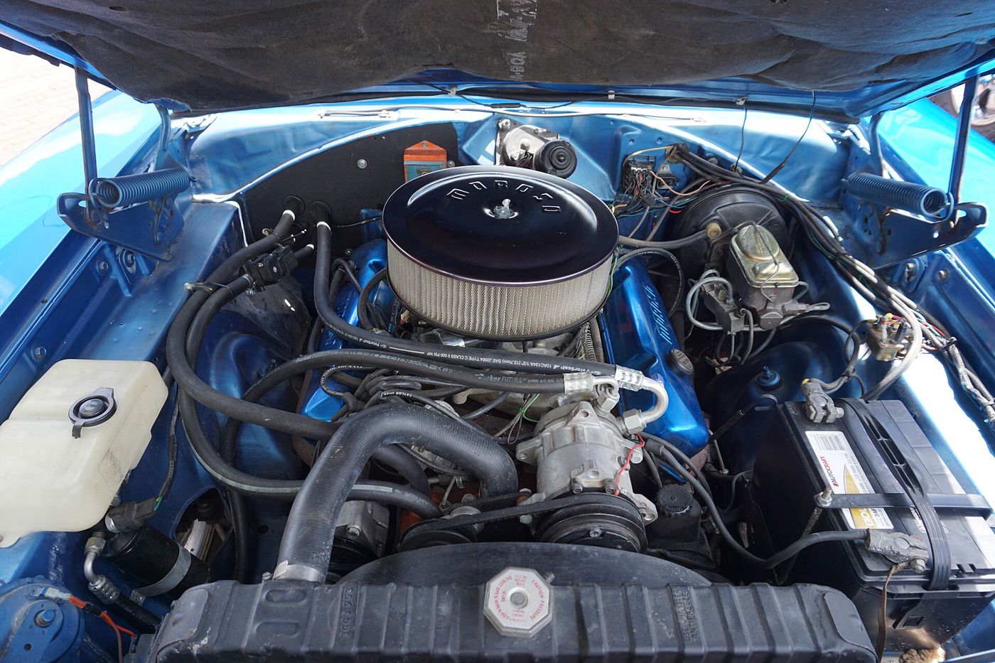 Engine compartment of a blue 1968 Dodge Charger showing the V8, chrome air cleaner and brake booster