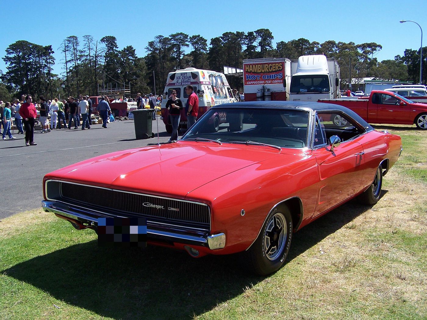 Red 1968 Dodge Charger with black vinyl roof from the front three-quarter, hidden-headlamp grille closed