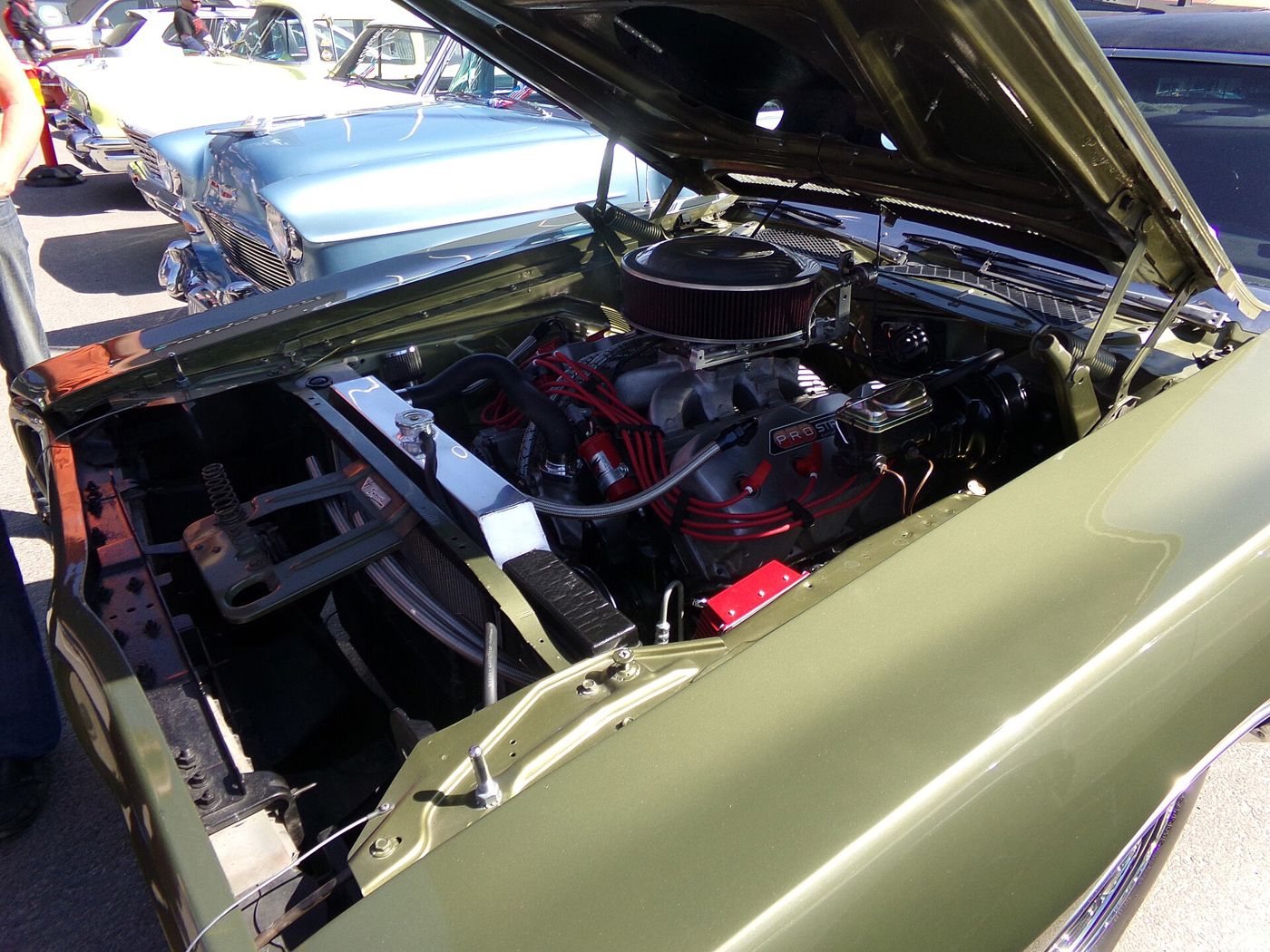 Engine bay of a green 1971 Dodge Charger with a black air cleaner and red spark plug wires