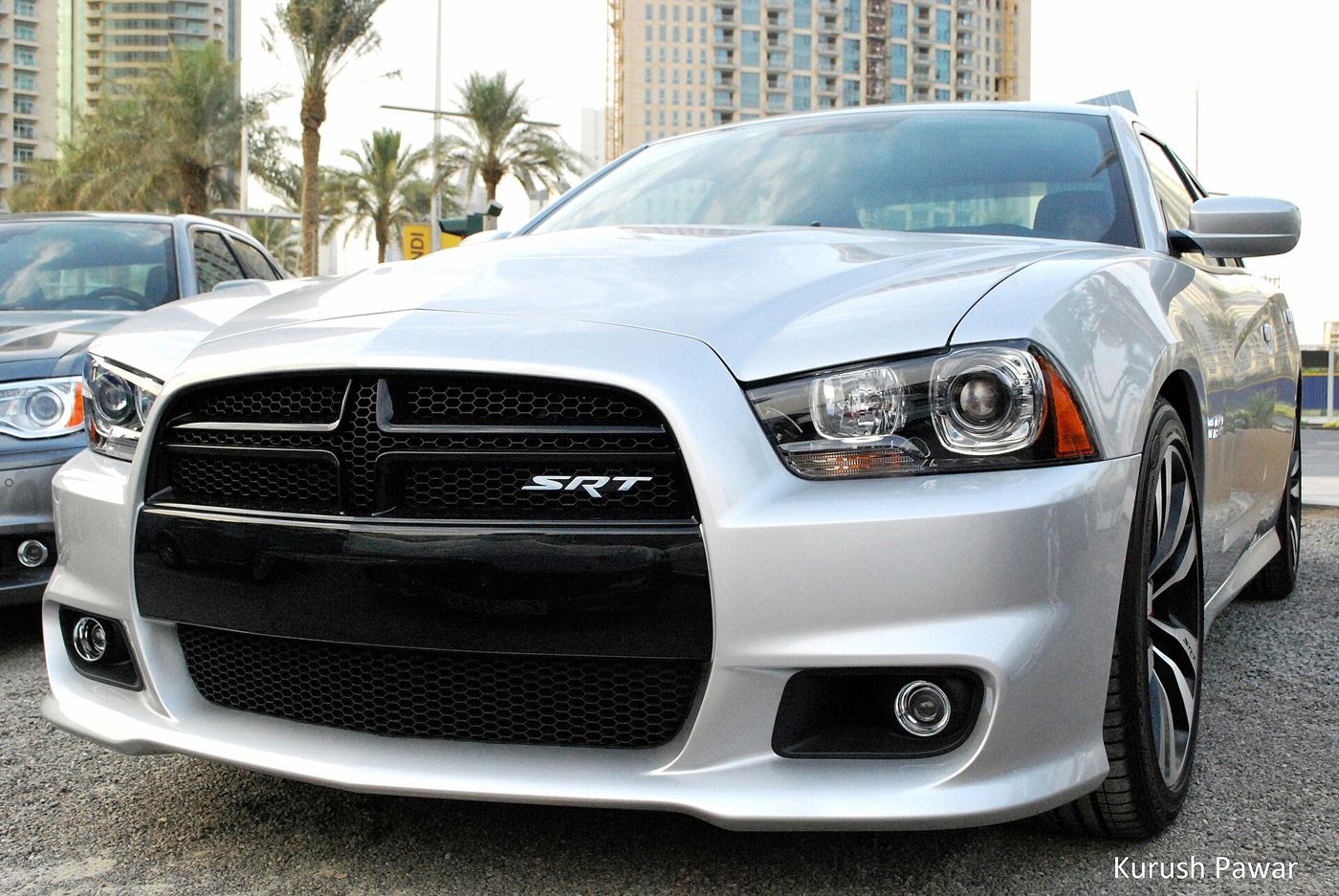 Silver 2012 Dodge Charger SRT8 seen close from the front, with the black crosshair grille and SRT badge