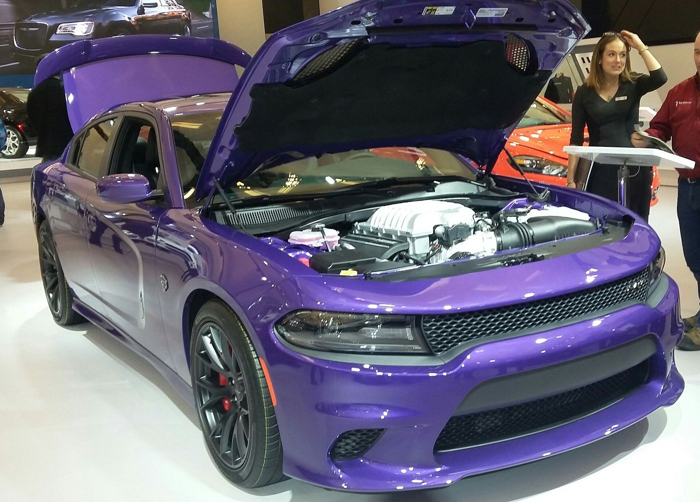Purple 2016 Dodge Charger SRT Hellcat at an auto show with the hood raised, showing the supercharged V8