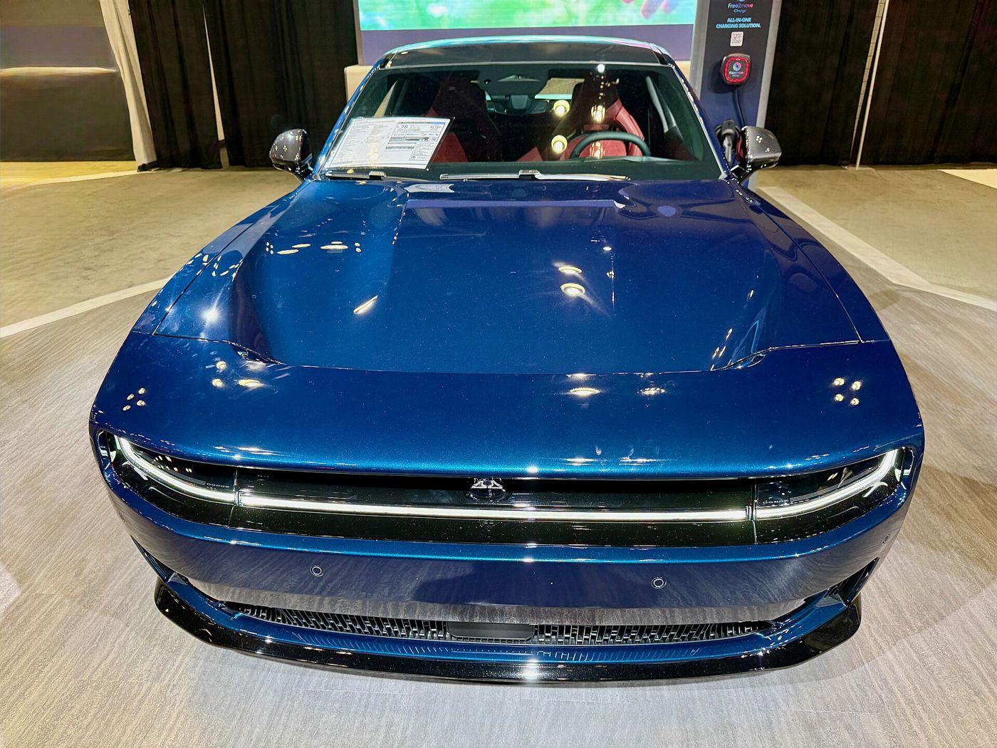 Head-on view of a blue 2025 Dodge Charger Daytona Scat Pack showing the full-width illuminated light bar and R-Wing opening