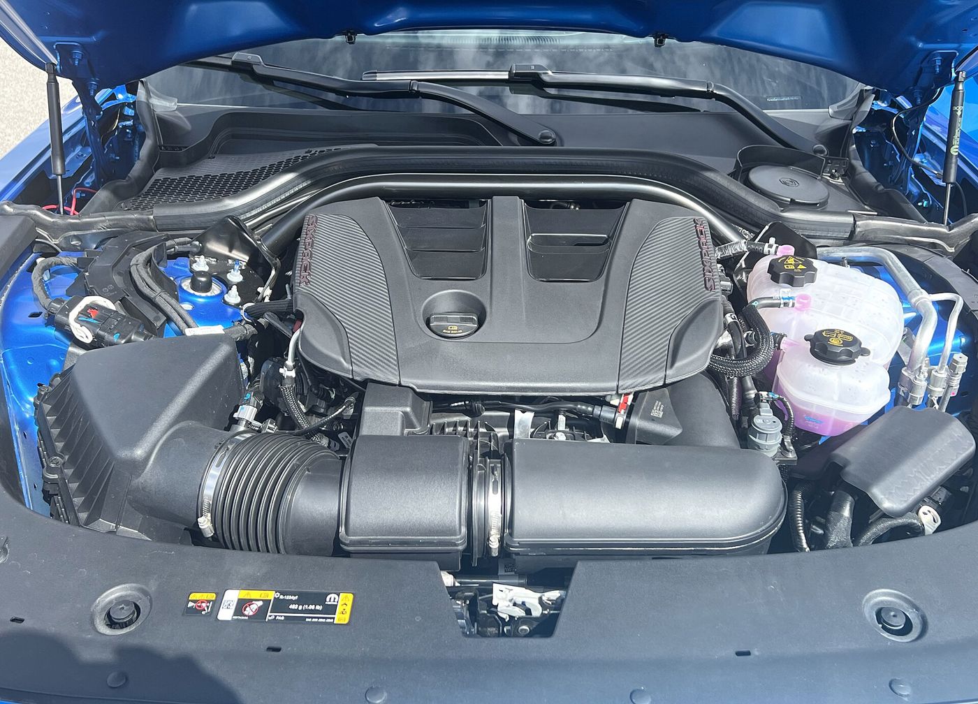 Engine bay of a blue 2026 Dodge Charger Sixpack showing the covered twin-turbo inline-six and large intake duct