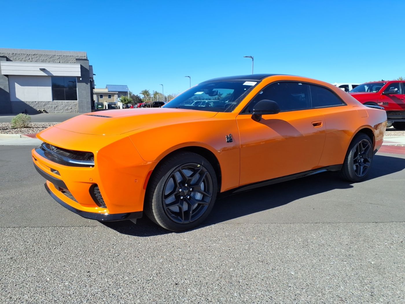 Orange 2026 Dodge Charger Scat Pack two-door in a parking lot, front three-quarter view