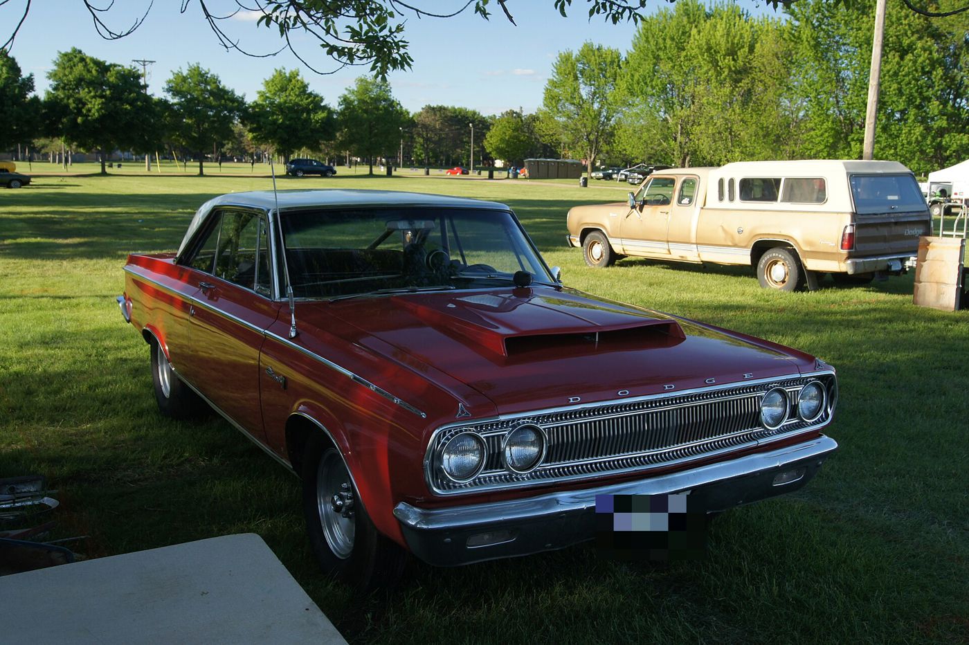Red 1965 Dodge Coronet 500 hardtop with a raised hood scoop, front three-quarter on grass