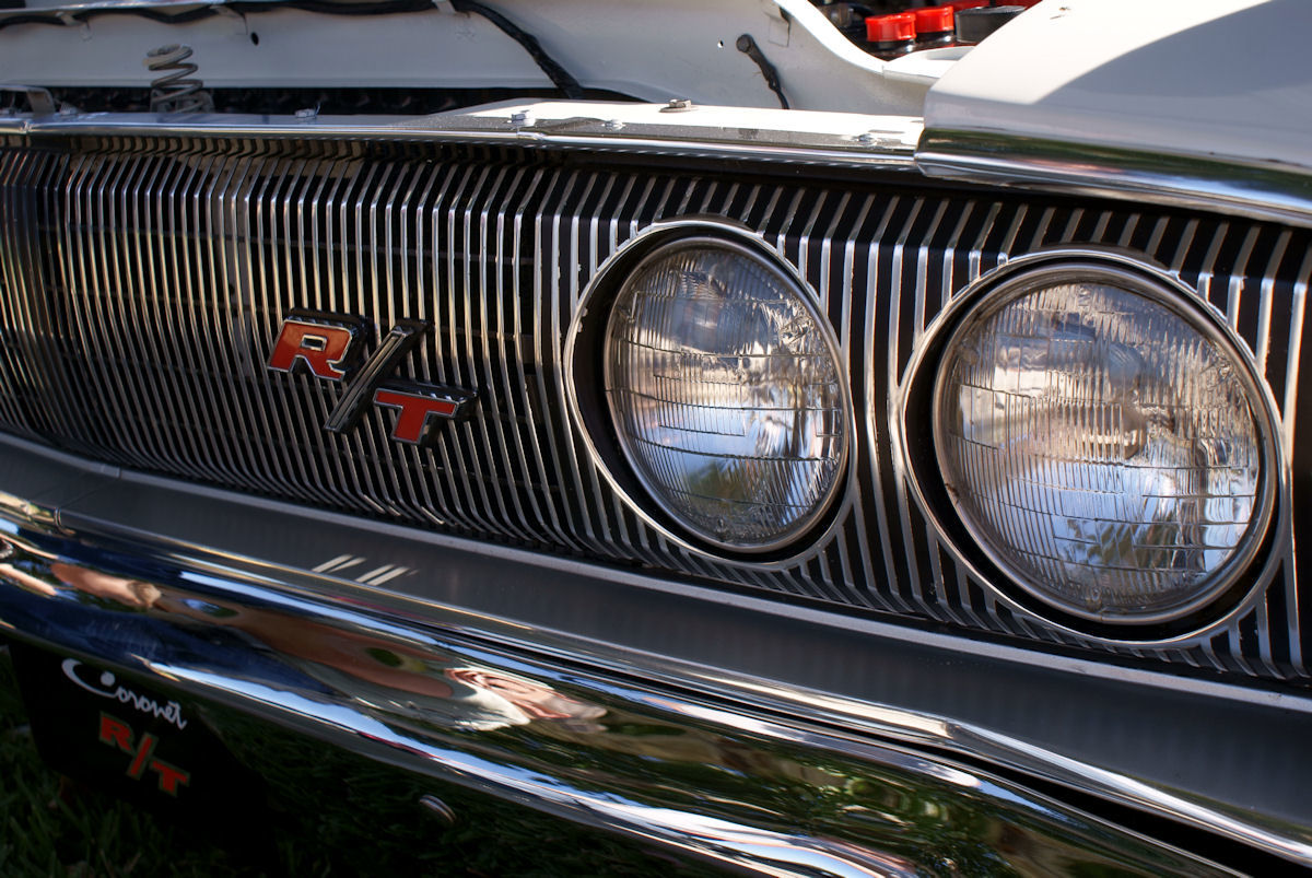 Close-up of the red R/T emblem on the vertical-bar grille beside the twin headlamps of a 1967 Dodge Coronet R/T