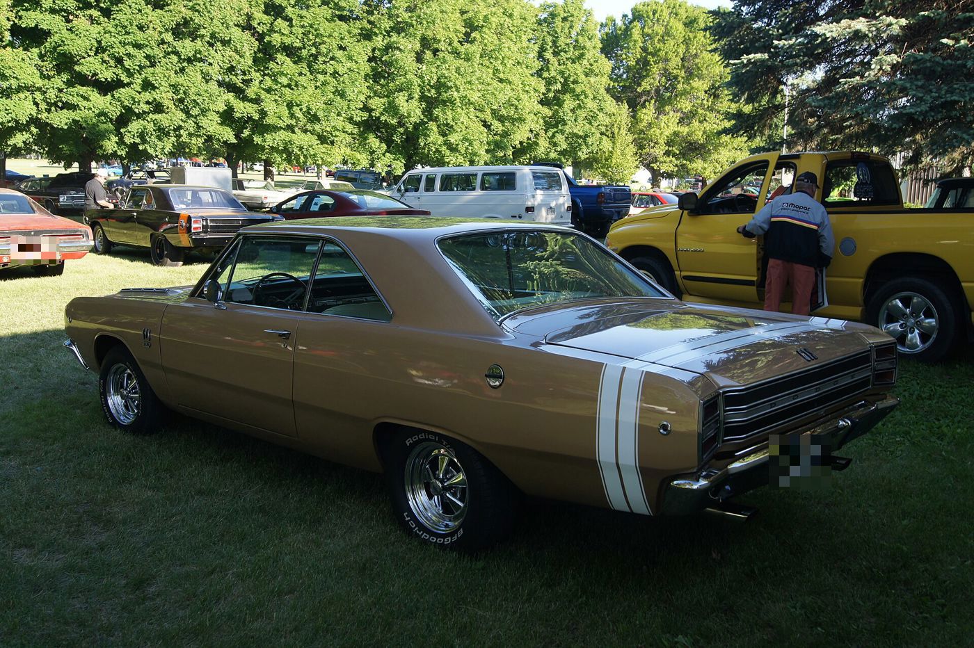 Gold 1968 Dodge Dart GTS on grass seen from the rear three-quarter, with a white bumblebee stripe