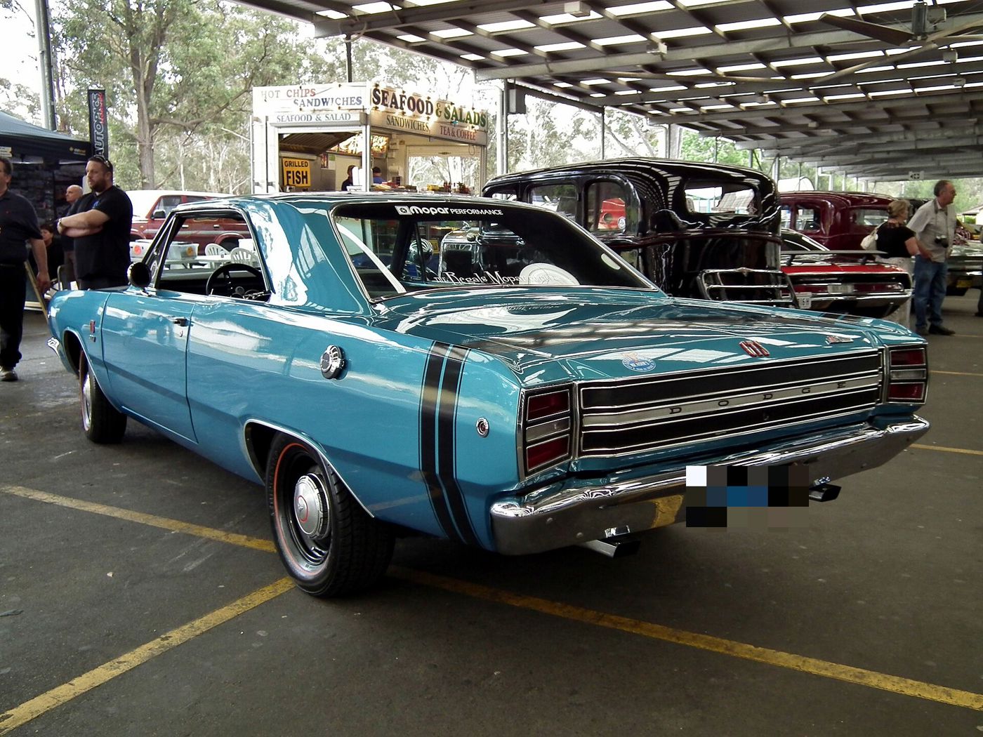 Blue 1968 Dodge Dart GTS from the rear three-quarter, showing the black bumblebee stripe around the tail and the GTS tail panel