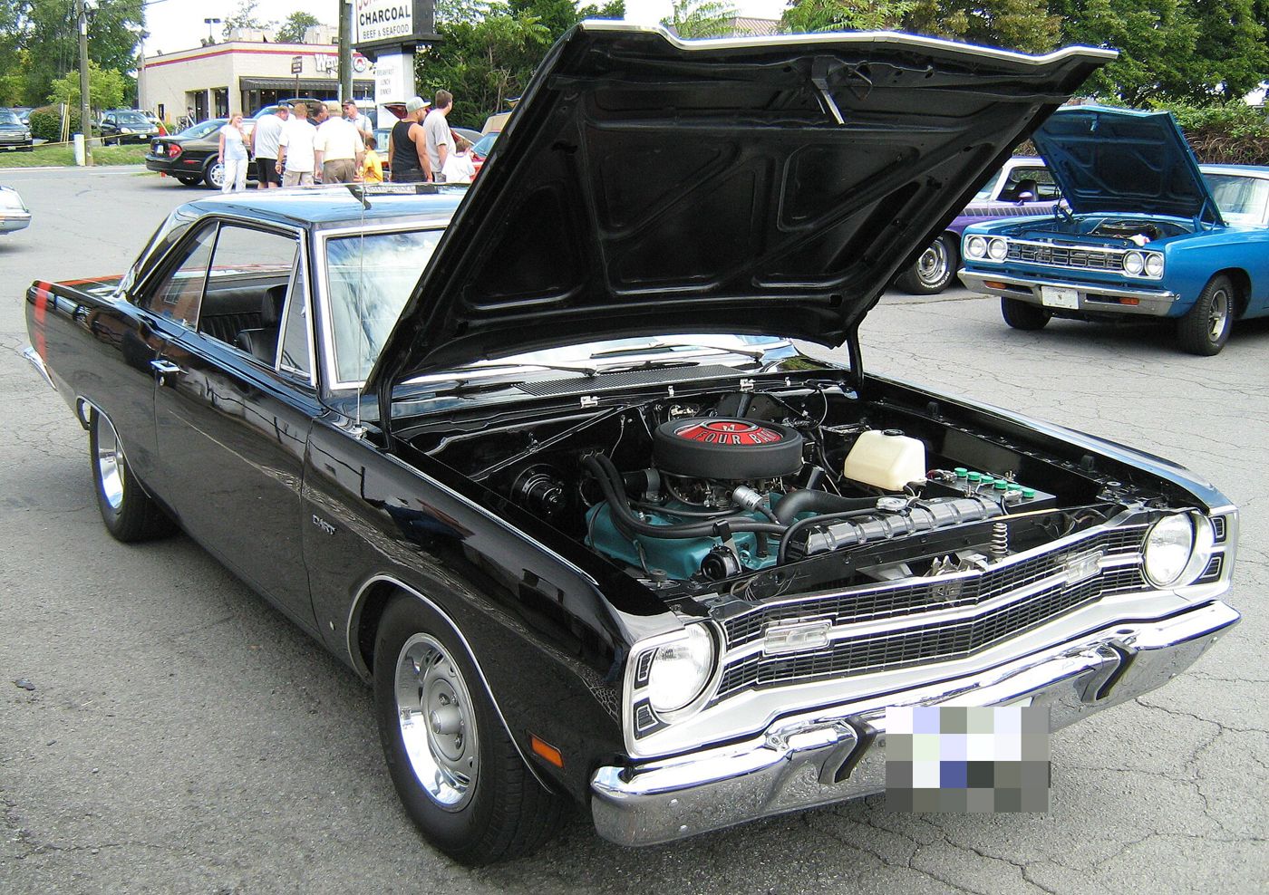 Black 1969 Dodge Dart Swinger 340 with the hood raised over its 340 V8, at an outdoor car show