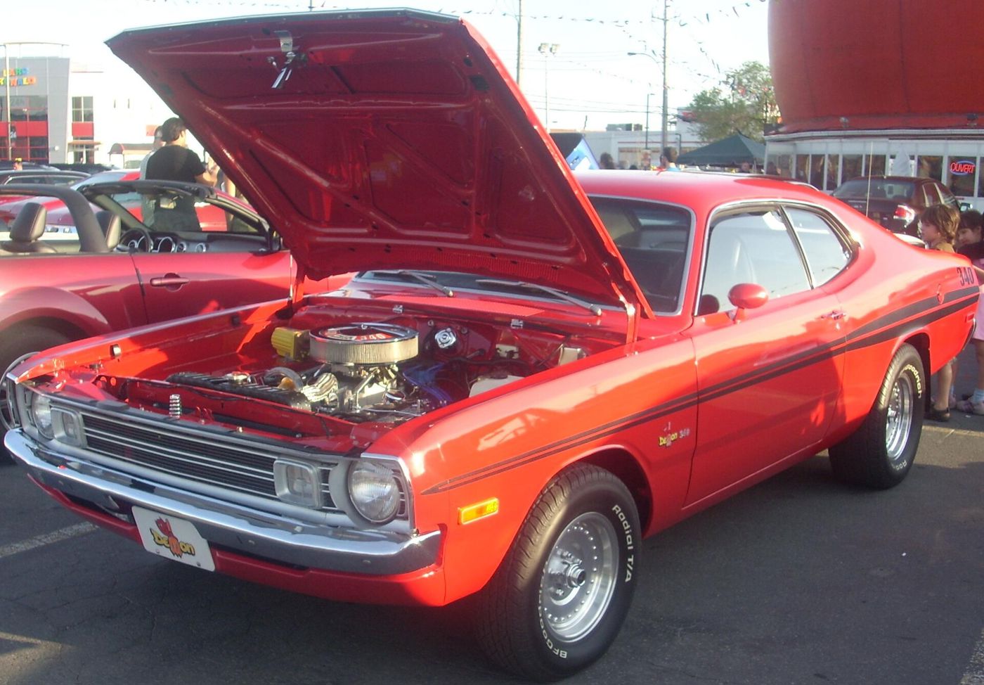 Red 1972 Dodge Demon 340 with black side stripes and the hood raised over its 340 V8
