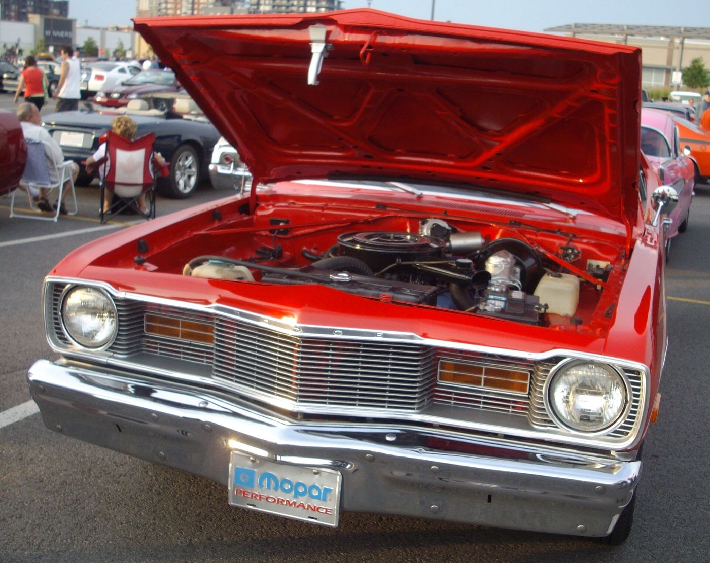 Red 1976 Dodge Dart seen close from the front with the hood raised over its V8