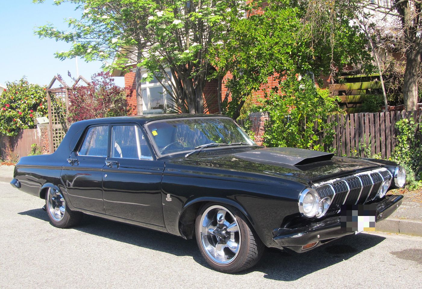 Black 1963 Dodge two-door sedan with the 1963 grille, an added hood scoop and custom wheels, front three-quarter