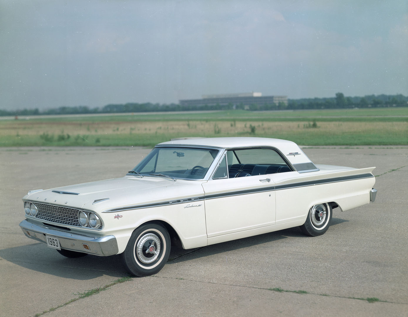White 1963 Ford Fairlane 500 Sports Coupe two-door hardtop on an airfield apron, front three-quarter view, with a 260 V8 emblem on the front fender