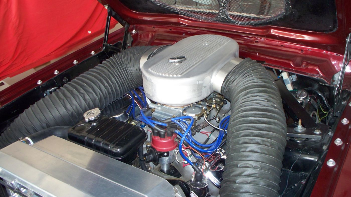 Engine bay of a 1964 Ford Fairlane Thunderbolt: a 427 V8 under a large aluminum air box fed by two flexible hoses from the front