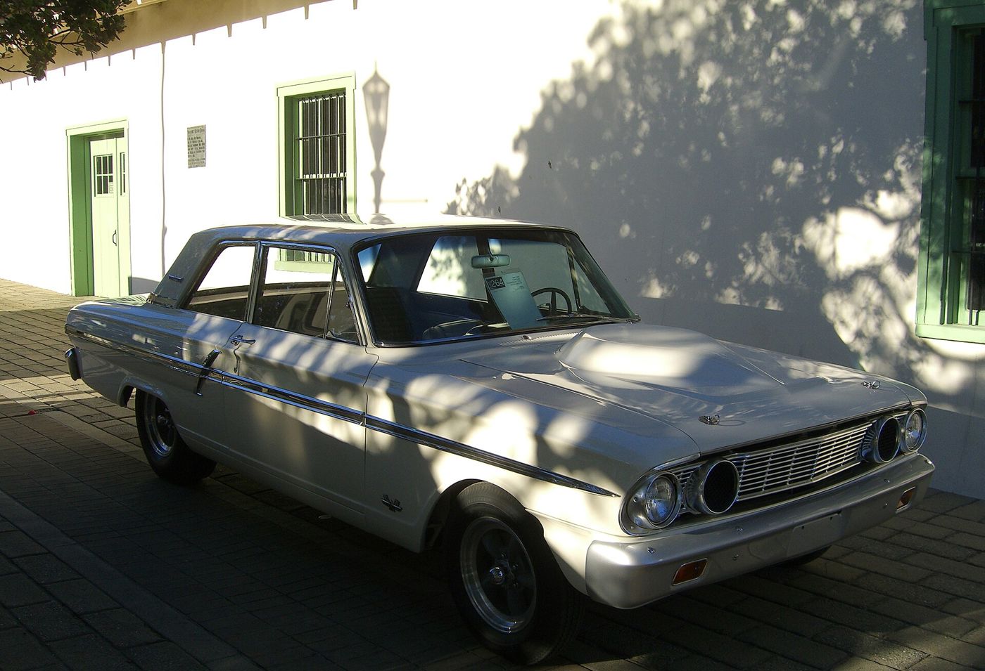 White 1964 Ford Fairlane Thunderbolt two-door sedan, front three-quarter, showing the teardrop hood bulge and the open inner-headlight air intakes