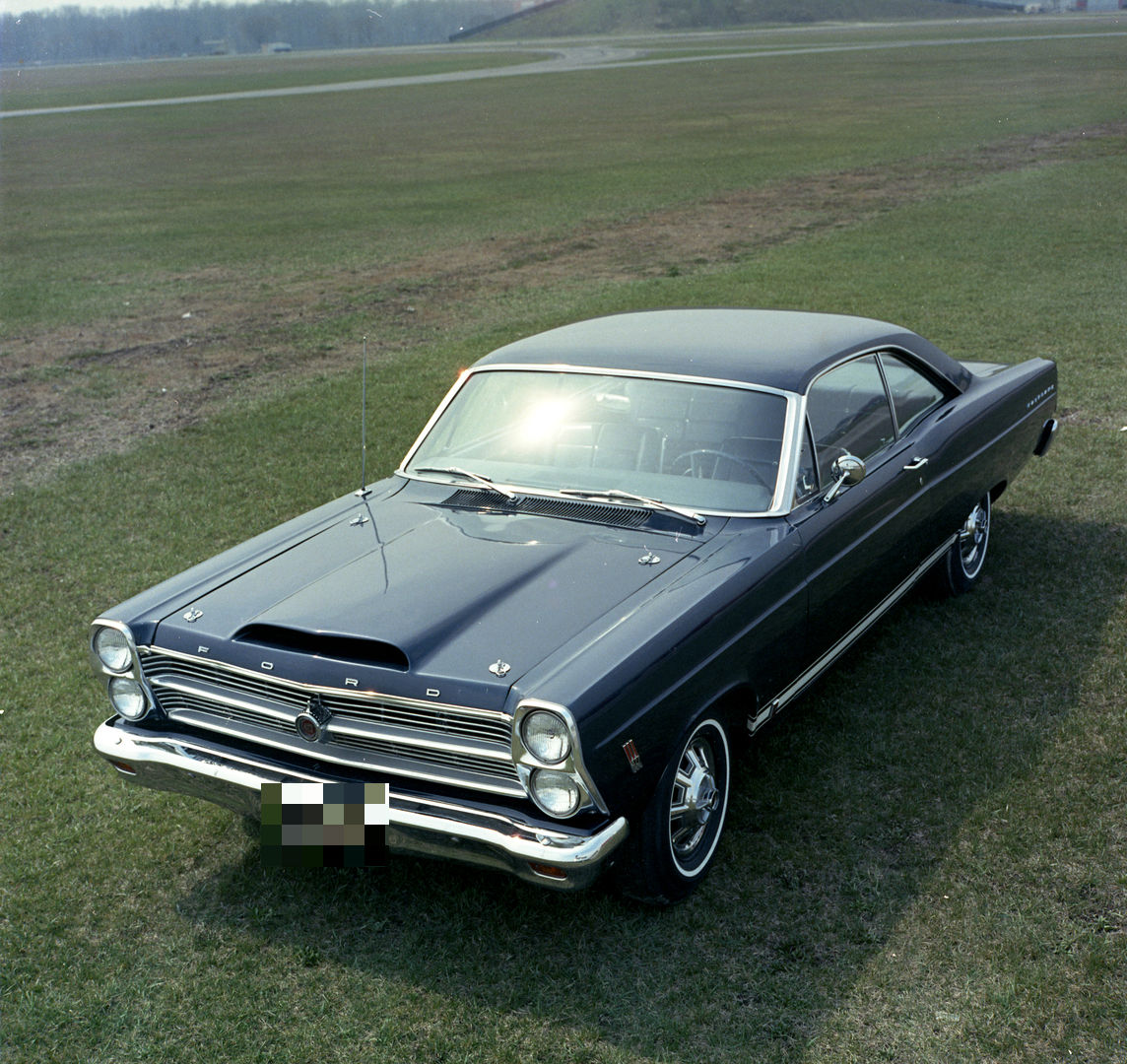 Dark blue 1966 Ford Fairlane two-door hardtop seen from a high front three-quarter on grass, showing the stacked headlights and the scooped hood of the 427 car