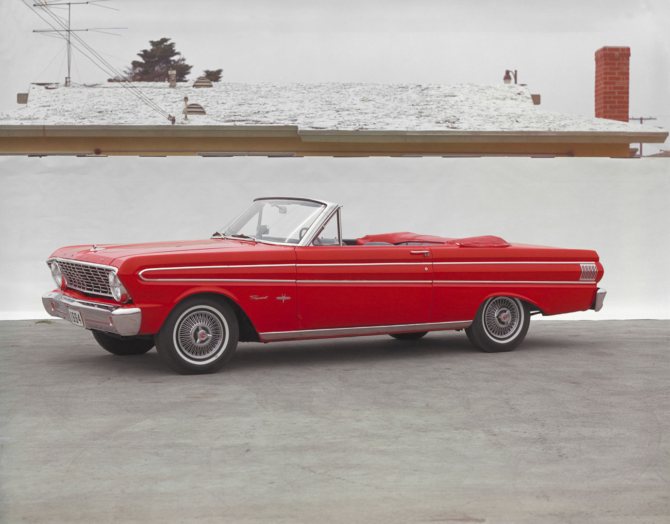 Red 1964 Ford Falcon Sprint convertible with the top down, seen from the front three-quarter, Sprint script on the front fender and wire wheel covers