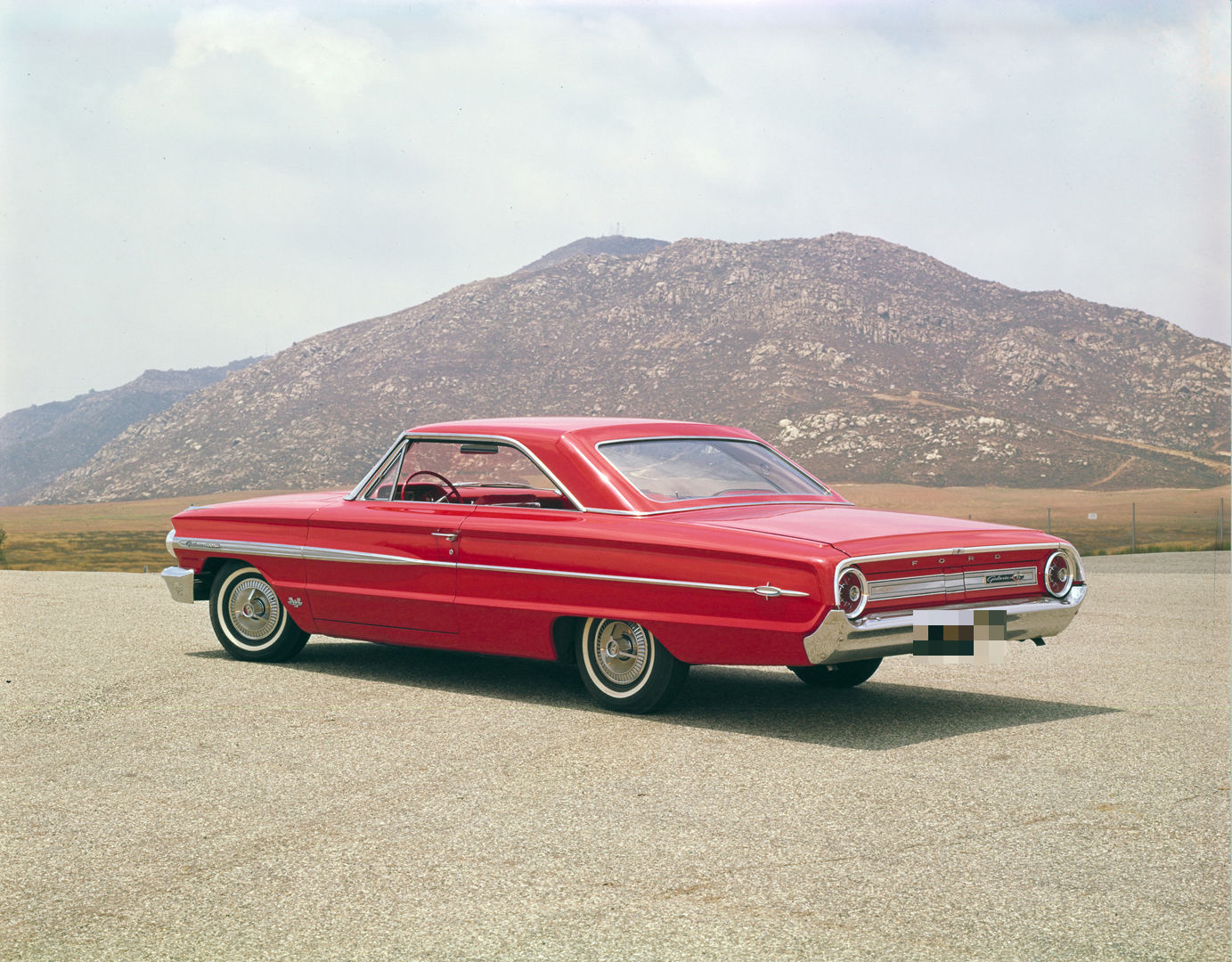 Red 1964 Ford Galaxie 500XL two-door hardtop seen from the rear three-quarter, showing the sloped roof and round taillights