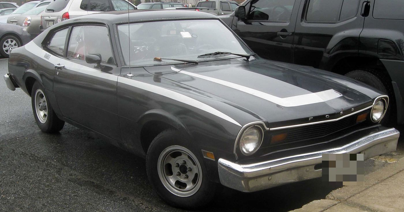 Dark grey Ford Maverick Grabber with a white hood stripe and GRABBER lettering on the rear roof pillar, front three-quarter view in a parking lot