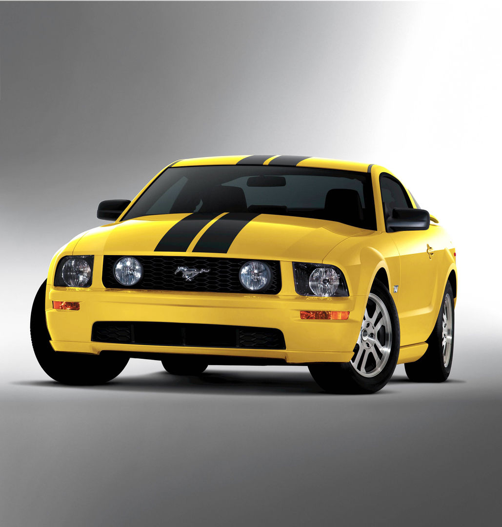 Yellow 2005 Ford Mustang GT coupe with black over-the-top stripes and grille-mounted fog lamps, front three-quarter studio view