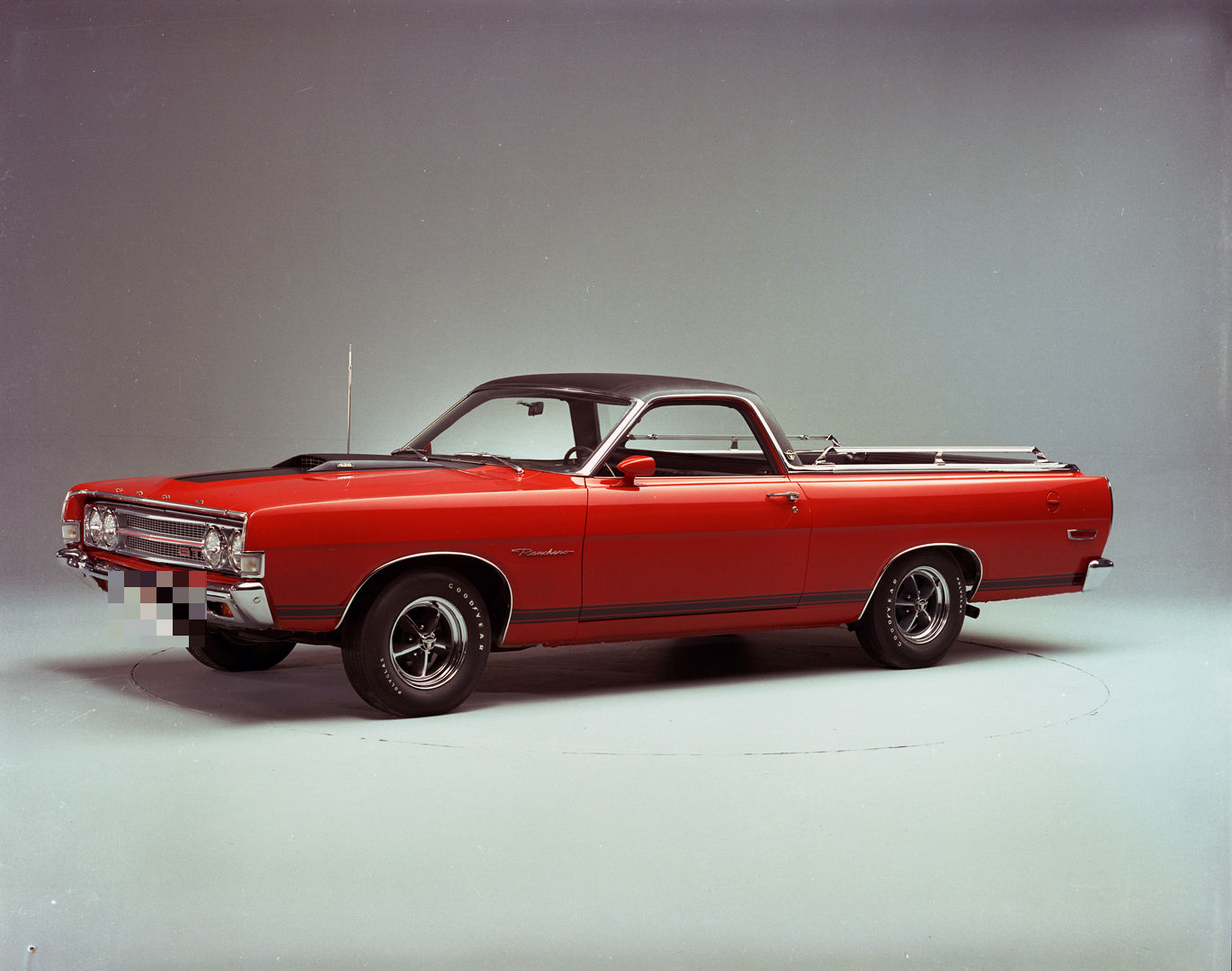 Red 1969 Ford Ranchero GT car-pickup with a black vinyl roof, hood scoop, GT grille badge and styled wheels, front three-quarter studio view