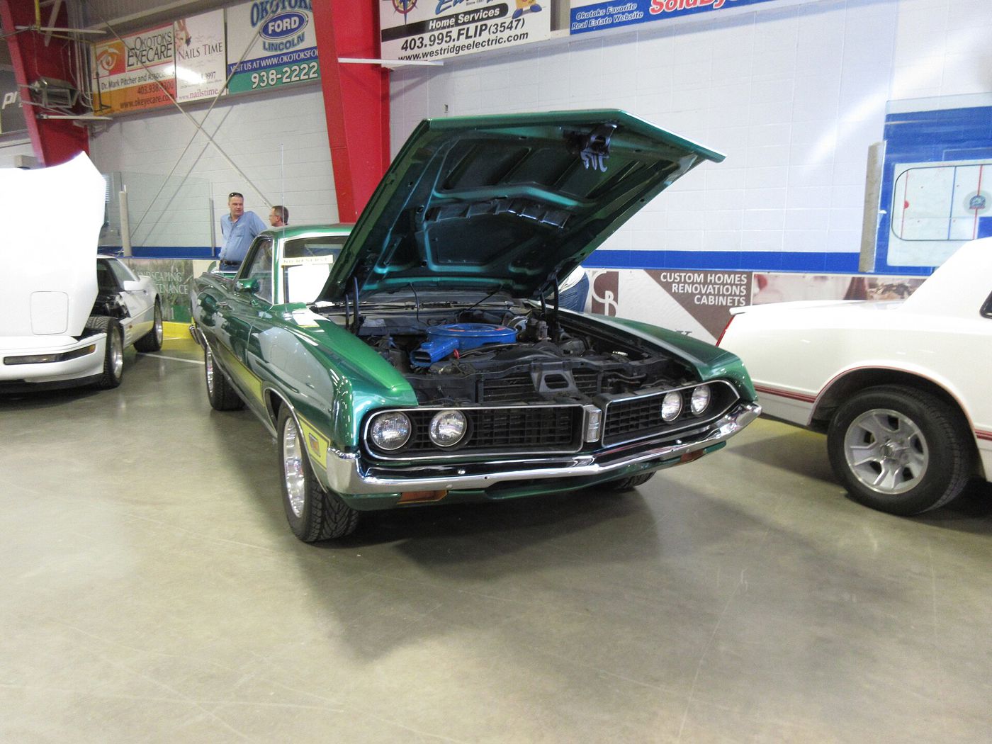 Green 1971 Ford Ranchero GT with the hood raised at an indoor auction, front three-quarter view showing the pointed grille and quad headlights