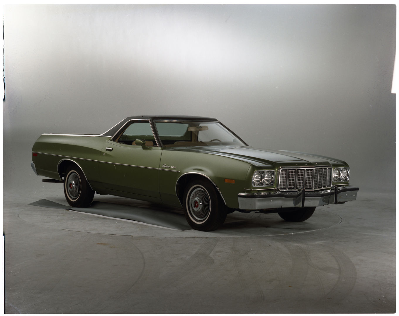 Green 1974 Ford Ranchero 500 with a dark vinyl roof in a studio, front three-quarter view, with the vertical-bar grille used from 1974