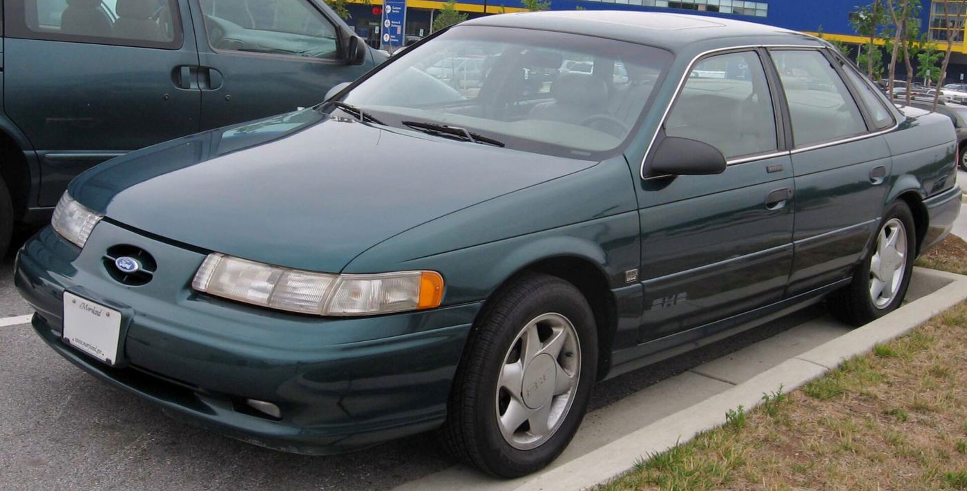 Dark green second-generation Ford Taurus SHO sedan parked at a curb, front three-quarter view, with SHO badge on the front door