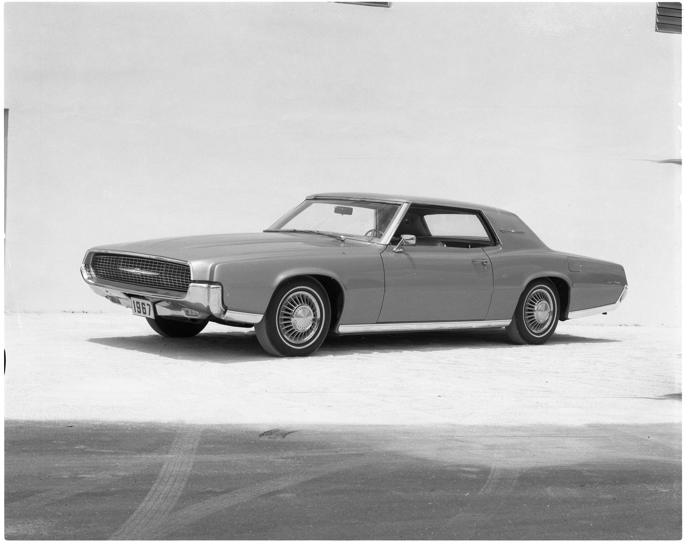 Black-and-white photo of a 1967 Ford Thunderbird two-door hardtop, front three-quarter view, showing the full-width grille with hidden headlamps
