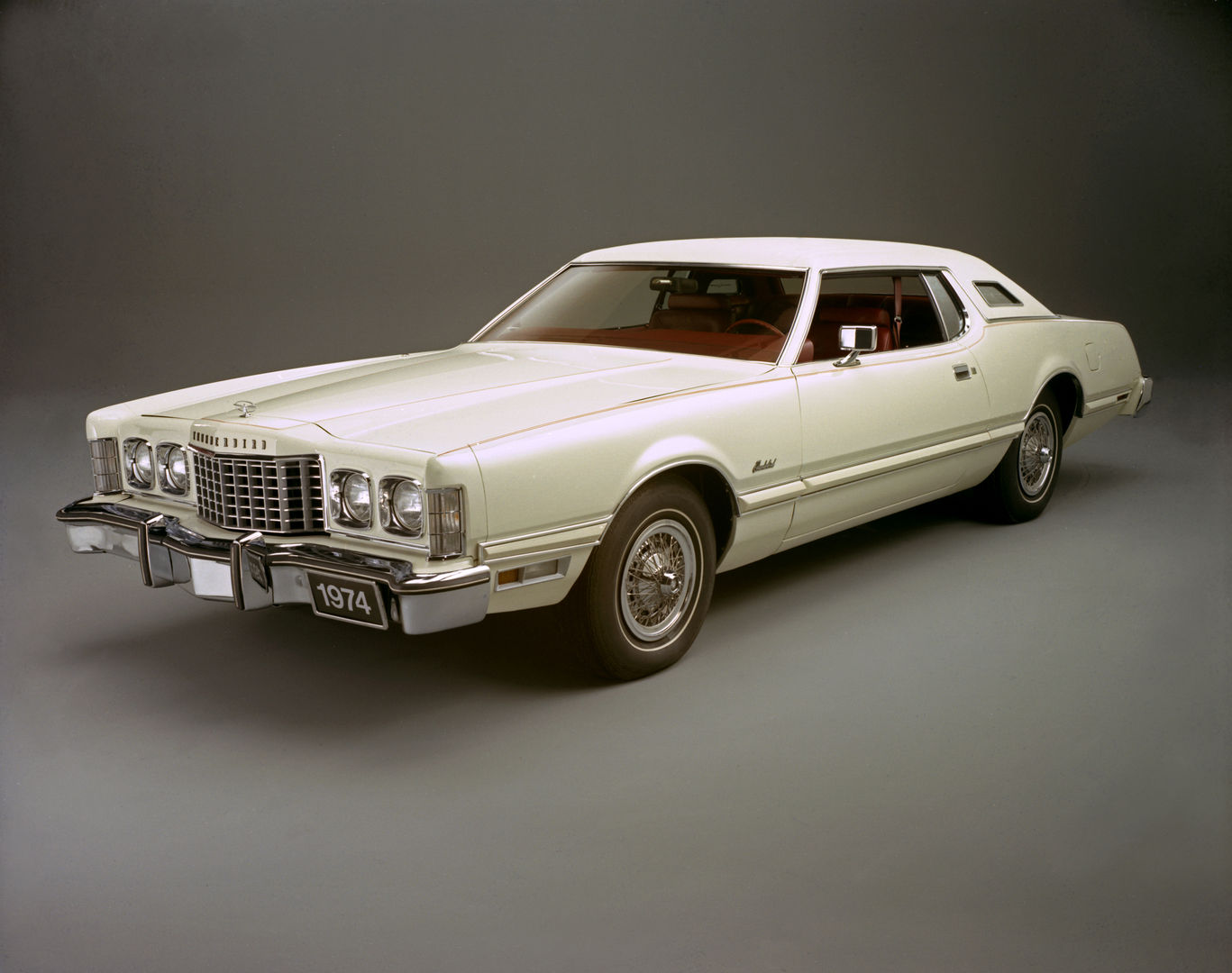 White 1974 Ford Thunderbird two-door with opera windows and a red interior, front three-quarter studio view