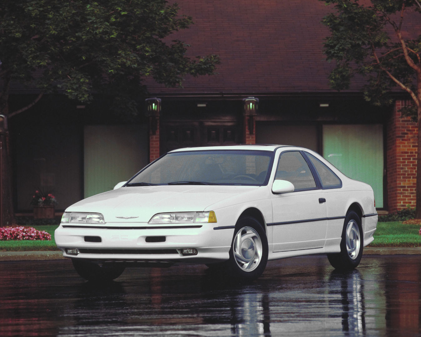 White 1990 Ford Thunderbird coupe on a wet driveway, front three-quarter view