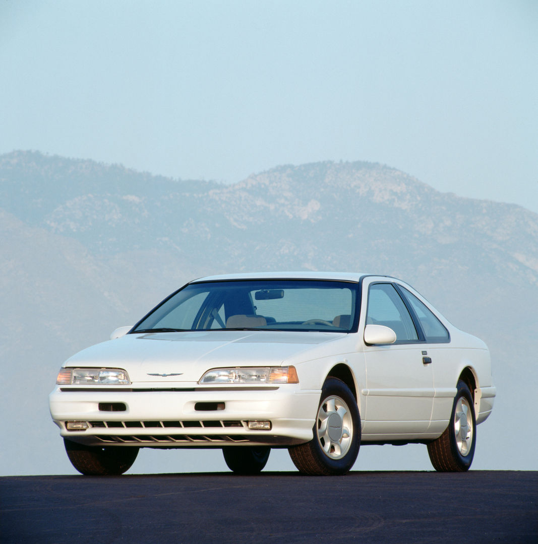White 1993 Ford Thunderbird LX coupe on pavement below mountains, front three-quarter view