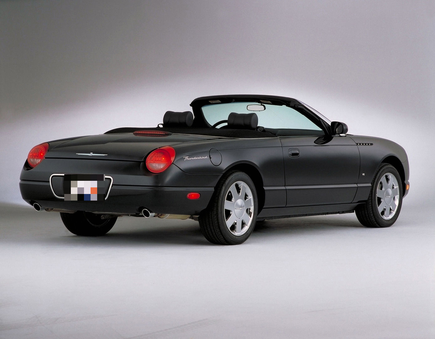 Black 2003 Ford Thunderbird convertible in a studio, rear three-quarter view with the top down