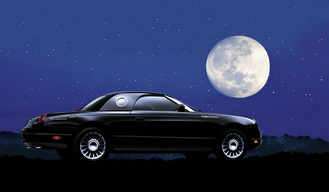 Black 2005 Ford Thunderbird 50th Anniversary Edition with the porthole hardtop fitted, side view under a full moon