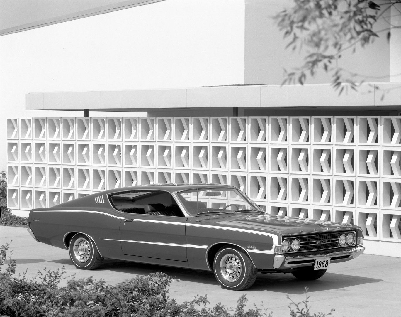 Black-and-white photo of a dark 1968 Ford Torino GT fastback, front three-quarter view, with a light body-side stripe and a 390 GT emblem on the front fender