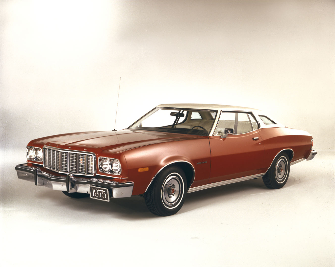 Copper 1975 Ford Gran Torino two-door hardtop with a white roof in a studio, front three-quarter view, with the vertical-bar grille and Gran Torino fender script