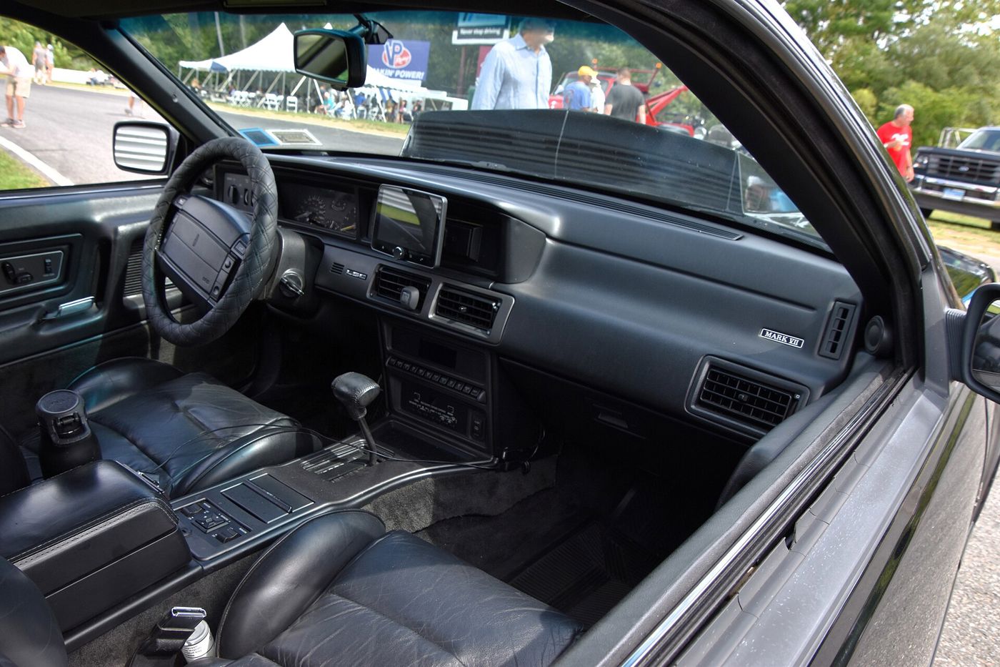 Black leather interior of a 1992 Lincoln Mark VII LSC seen through the open driver's door, showing the dashboard, floor console and shifter
