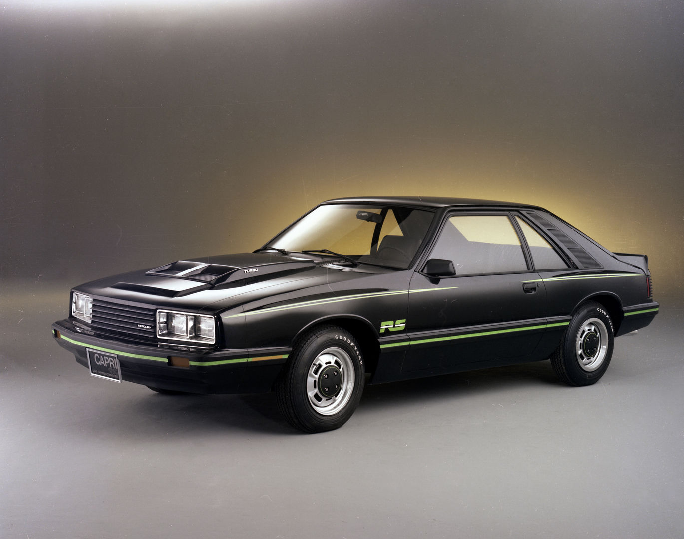 Black 1980 Mercury Capri RS Turbo hatchback with green pinstripes, a TURBO hood bulge and RS decal, front three-quarter studio view