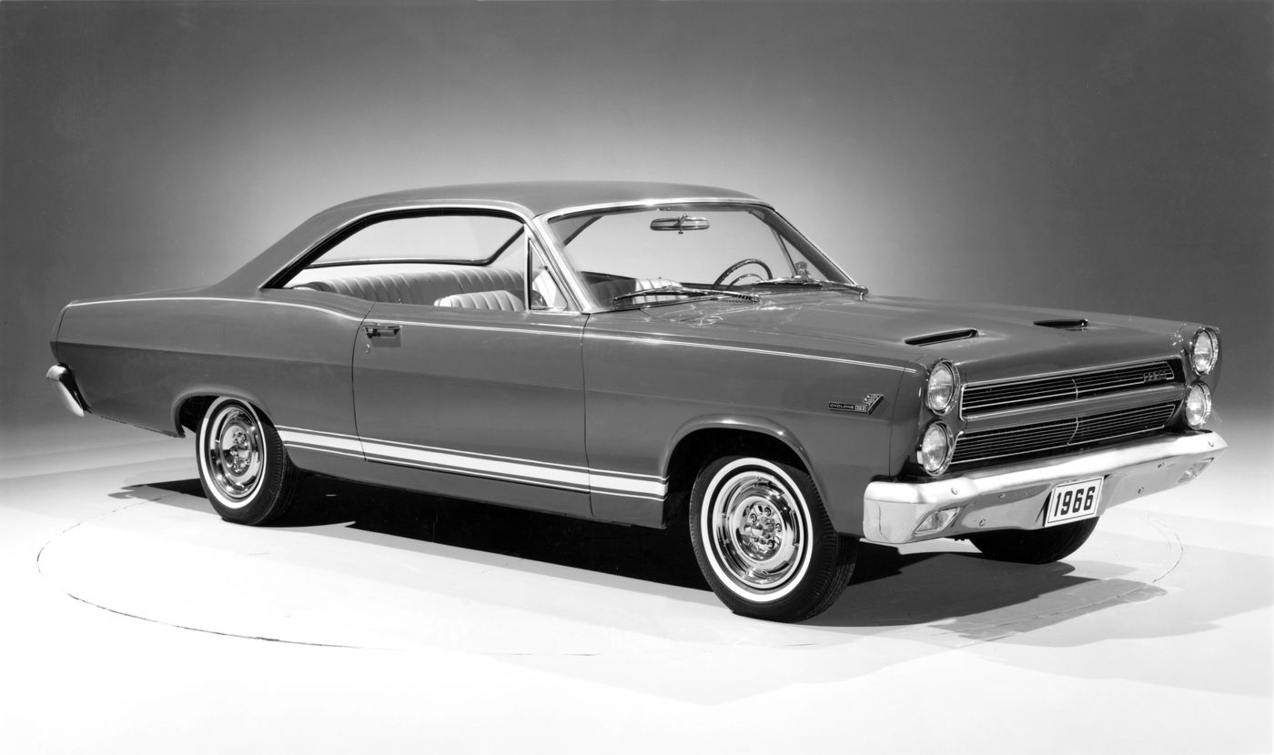 Black-and-white studio photo of a 1966 Mercury Comet Cyclone GT two-door hardtop, low front three-quarter view, showing the stacked headlights and the twin-scoop fiberglass hood