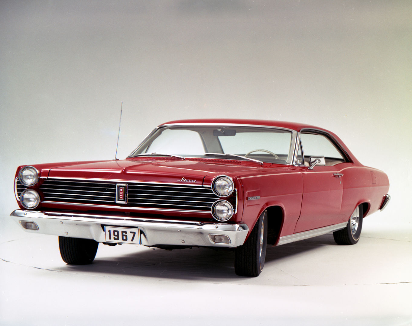 Red 1967 Mercury Cyclone two-door hardtop in a studio, close front three-quarter view, with stacked quad headlights and a horizontal-bar grille