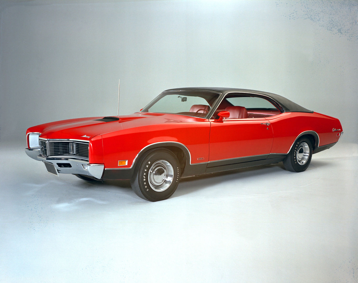 Red 1970 Mercury Cyclone GT two-door hardtop with a black roof and concealed headlights, front three-quarter studio view