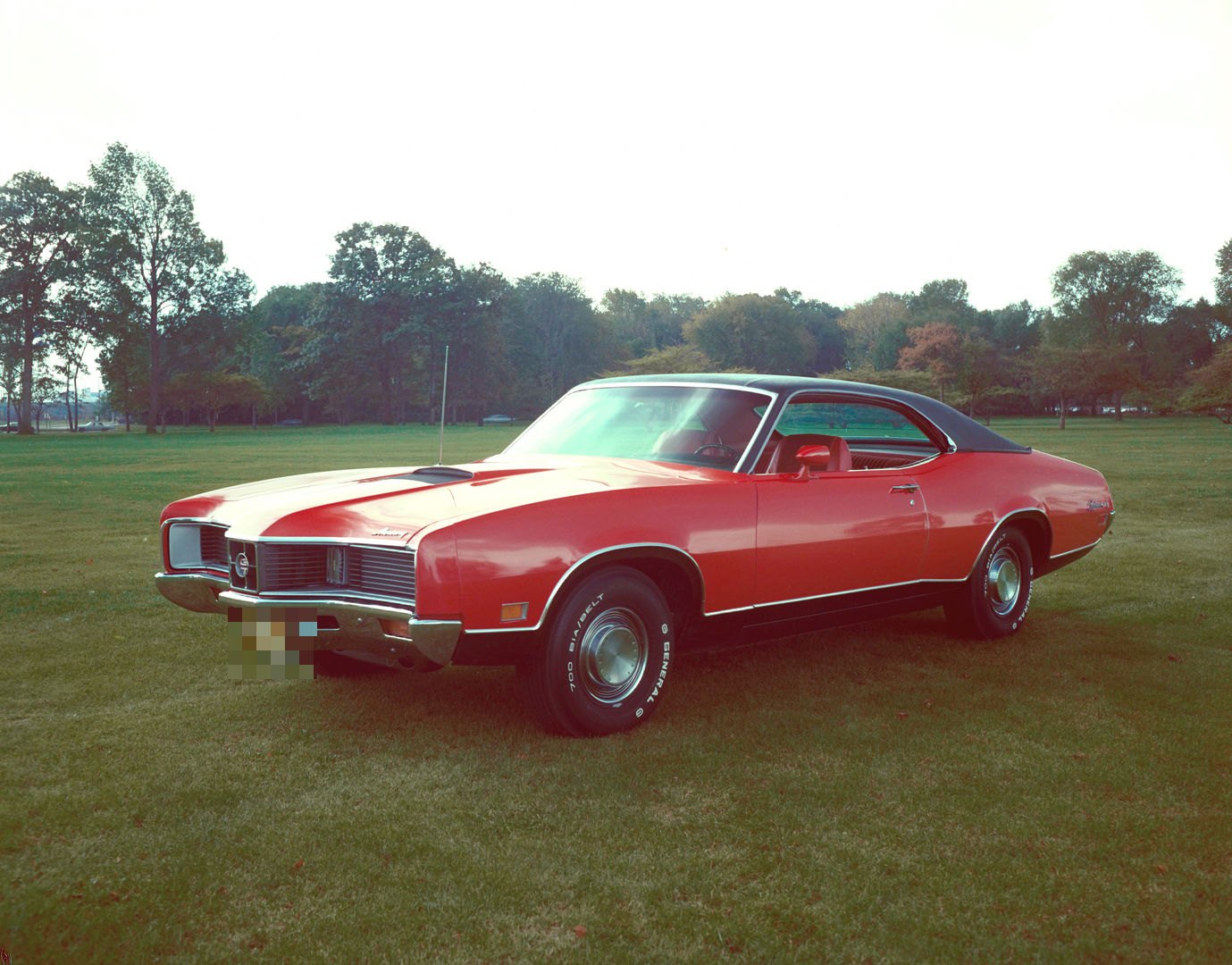 Red 1971 Mercury Cyclone GT two-door hardtop with a black roof on a lawn with trees behind, front three-quarter view
