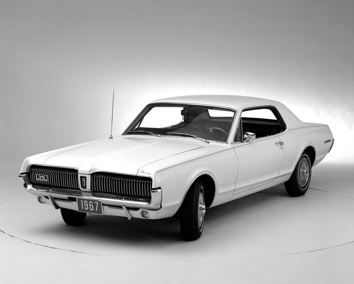 Black-and-white studio photo of a white 1967 Mercury Cougar hardtop, front three-quarter view, showing the electric-shaver grille with hidden headlights