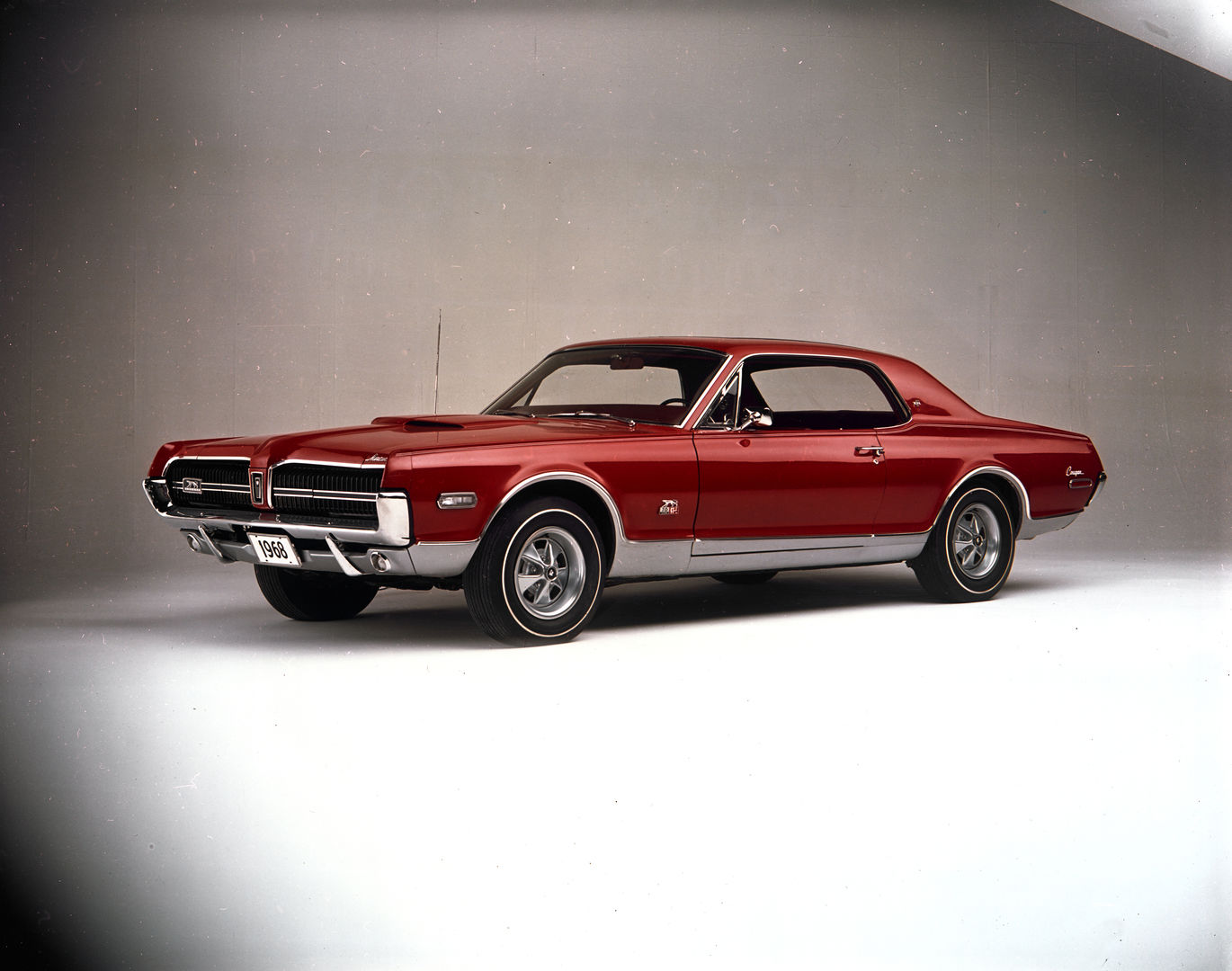 Red 1968 Mercury Cougar XR-7 GT-E hardtop with a hood scoop, lower-body silver paint and styled wheels, front three-quarter studio view