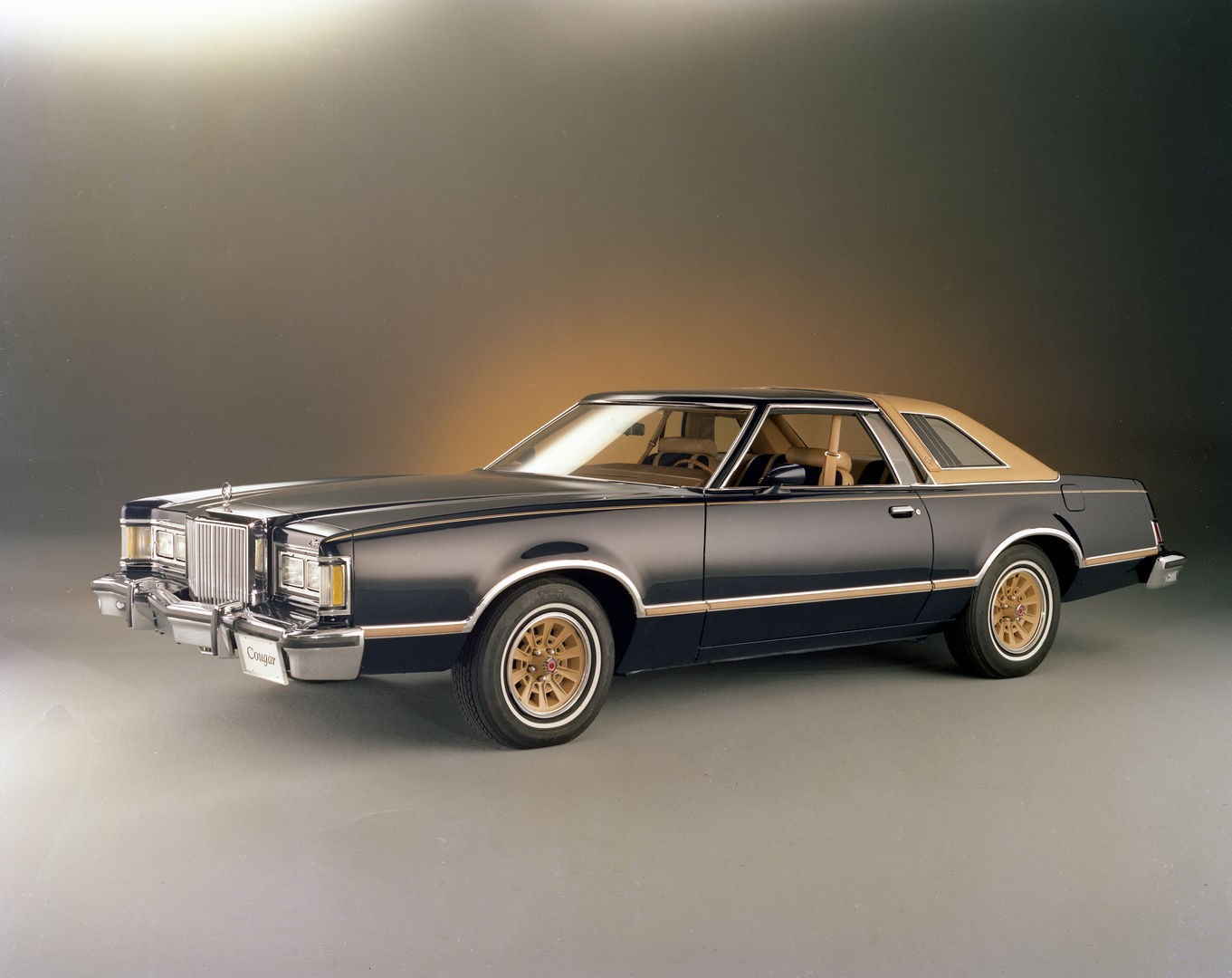 Black 1978 Mercury Cougar XR-7 with gold accent stripes, a tan roof and gold wheels, front three-quarter studio view