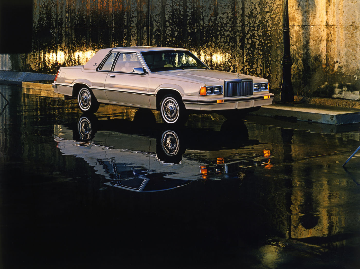 Silver 1982 Mercury Cougar XR-7 GS coupe beside a pool reflecting lamps at night, front three-quarter view