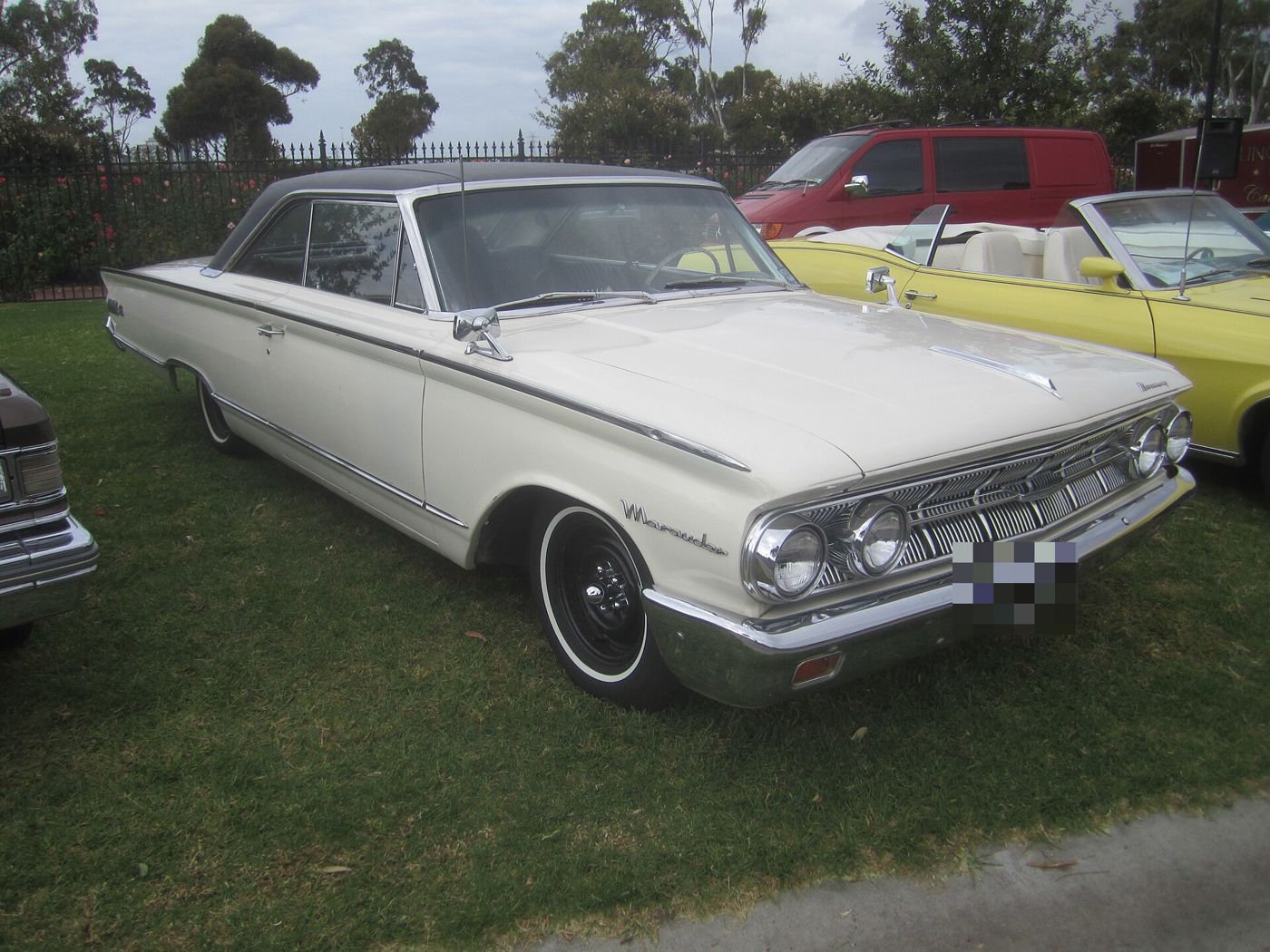 White 1963 Mercury Marauder two-door hardtop with a black roof and Marauder script on the front fender, front three-quarter view on grass at a car show