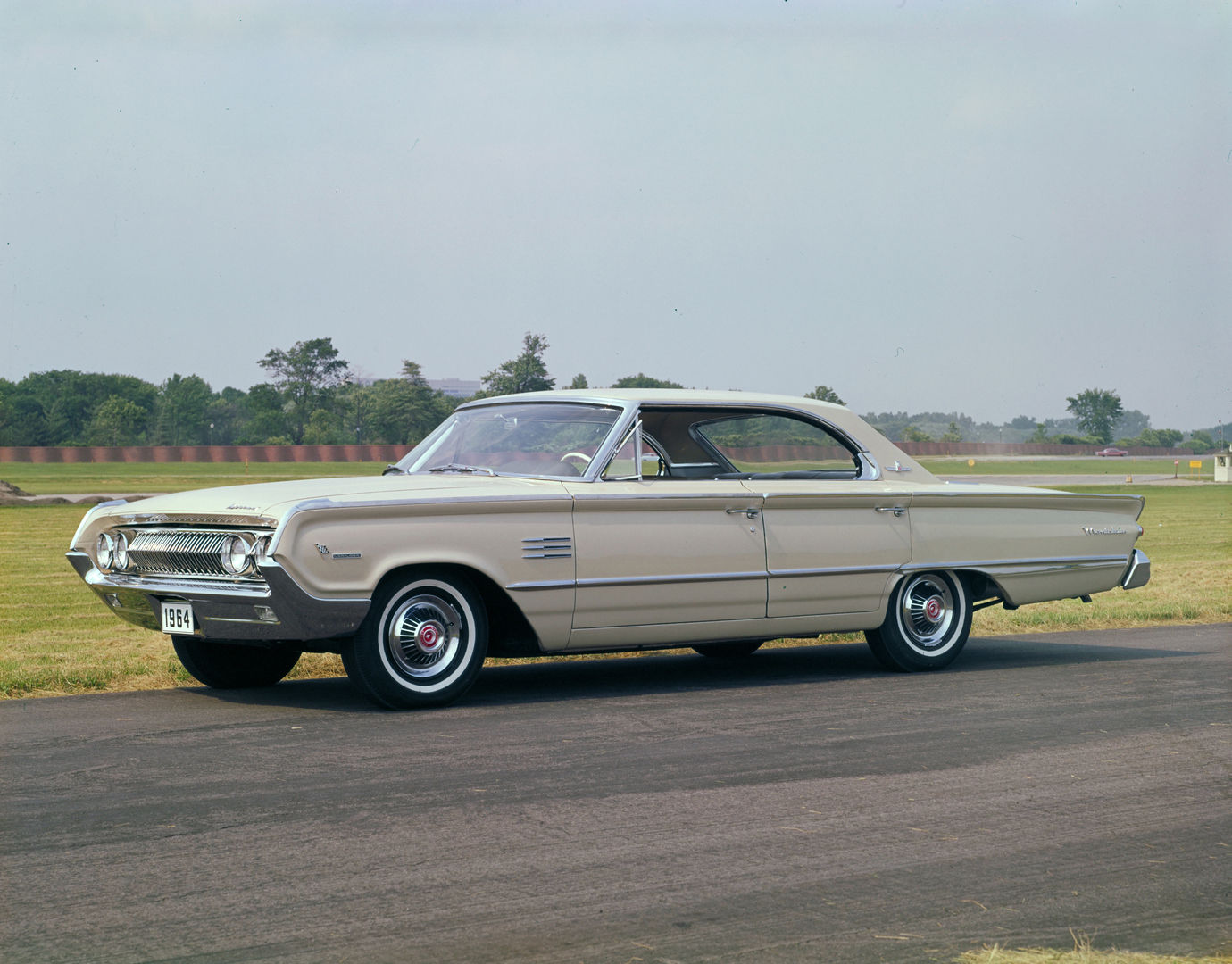 Cream 1964 Mercury Montclair Marauder four-door hardtop on a test-track apron, front three-quarter view