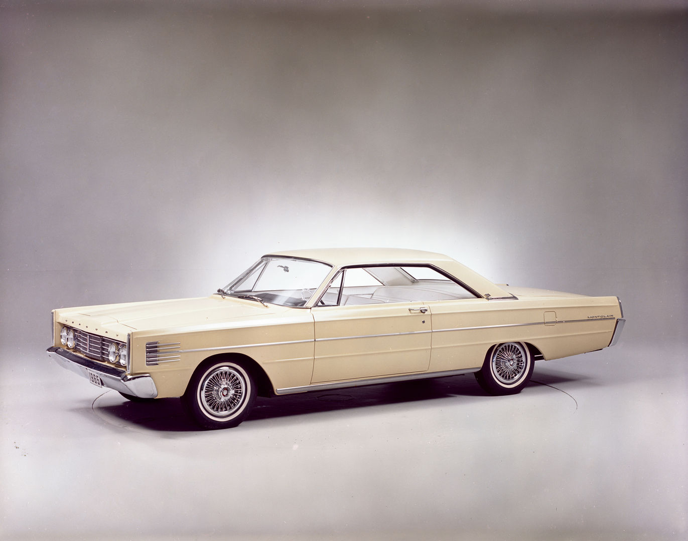 Cream 1965 Mercury Montclair Marauder two-door hardtop with wire wheel covers, front three-quarter studio view showing the squared-off 1965 body
