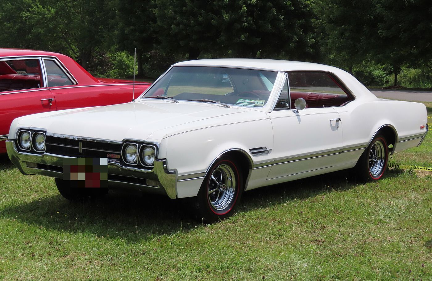 White 1966 Oldsmobile 4-4-2 hardtop with red-line tires, front three-quarter, on grass